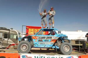 Phil Blurton and co-driver celebrating on podium after winning bitd bluewater desert challenge